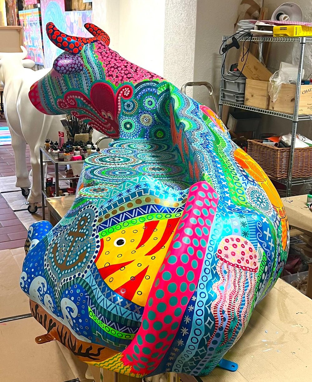 Vache Kuhtag couchée peinte de poissons en pointillisme