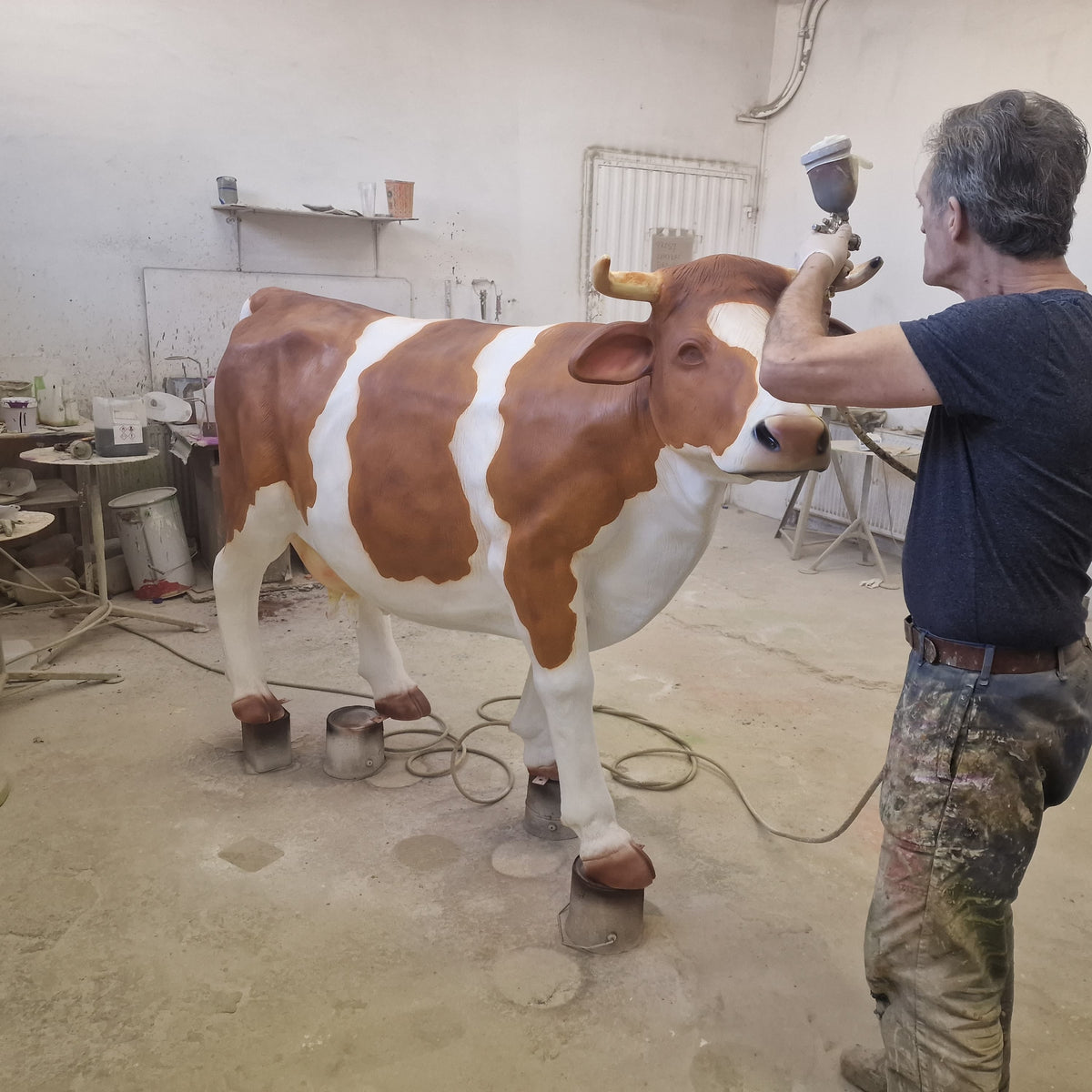 Peintre de l’atelier appliquant la couleur au pistolet sur une vache Kuhtag