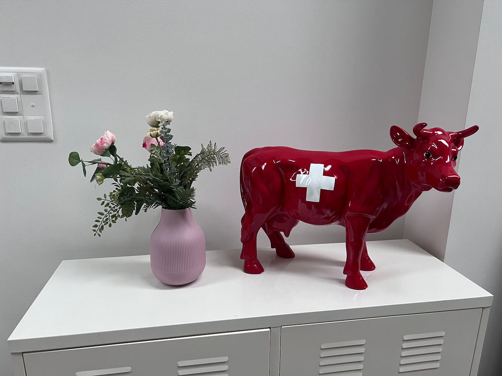 Petite vache Kuhtag à croix suisse sur un meuble