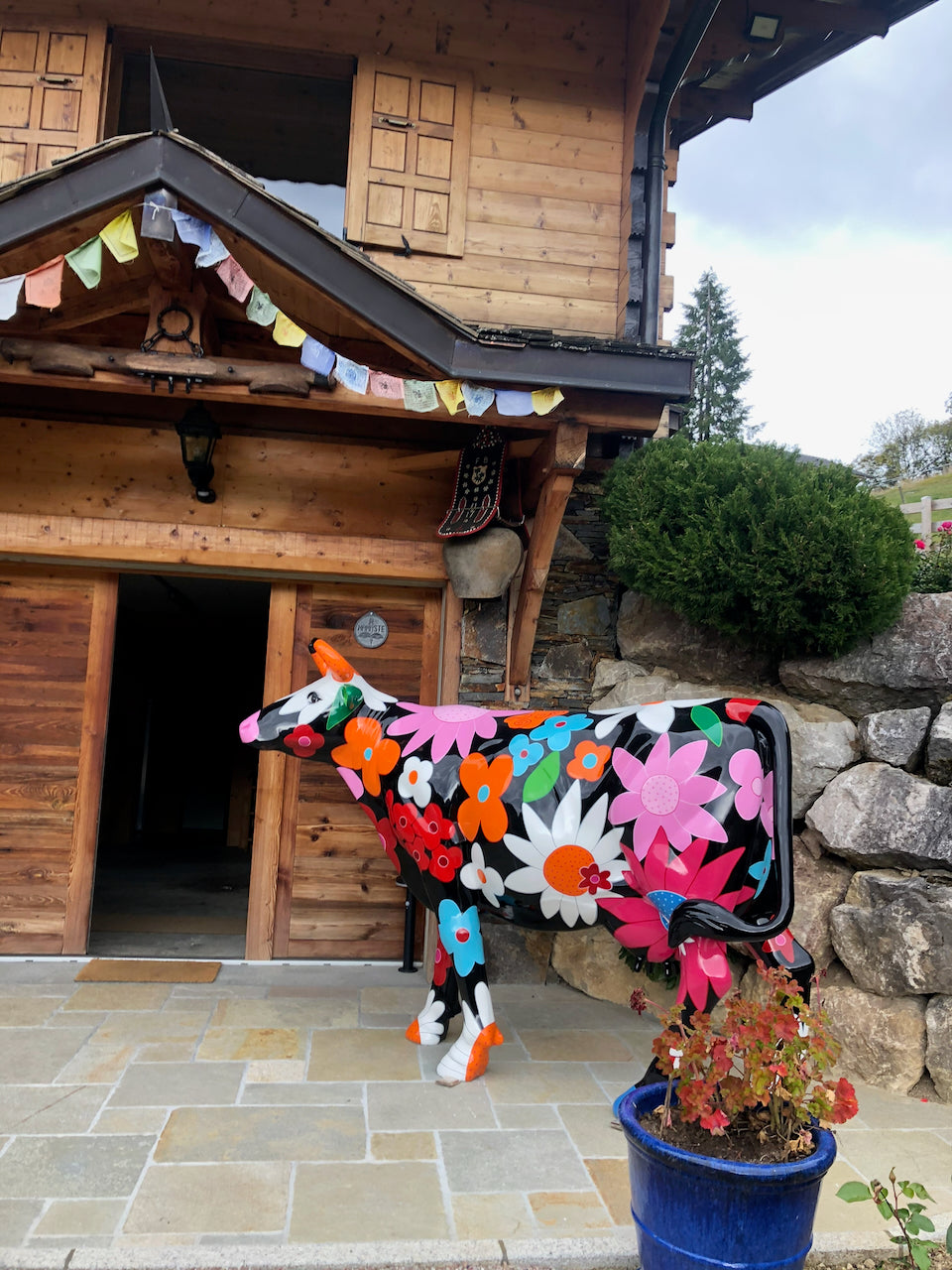 Vache Kuhtag à fleurs devant un chalet