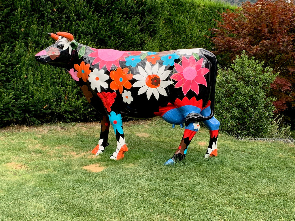 Vache Kuhtag à fleurs fond noir dans un jardin