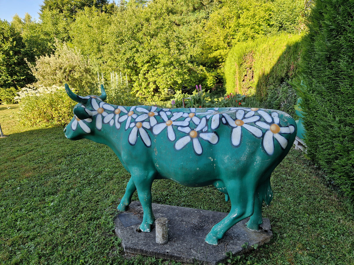 Vache en résine à marguerites abîmée par les intempéries, avant rénovation
